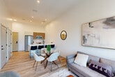 This thoughtfully designed one-bedroom, one-bathroom unit in Haverhill, MA offers a modern aesthetic with a clean, open-concept layout that seamlessly connects the kitchen, dining, and living areas. Light wood-tone flooring flows throughout, complemented by crisp white walls and soaring ceilings that enhance the sense of space and airiness.

The kitchen serves as a central focal point, anchored by a large island with white quartz countertops and bar seating for three. It is fully equipped with stainless steel appliances — including a full-size refrigerator, range, microwave, and dishwasher — and accented by warm wood upper cabinetry with a classic subway tile backsplash. The adjacent dining and living areas benefit from generous natural light streaming through large, black-framed windows that frame outdoor views.

The bedroom is a tranquil retreat featuring oversized windows with scenic views, elevated ceilings, and direct access to a utility room with stacked in-unit washer and dryer via a stylish sliding barn door. Two closets provide ample storage. The bathroom offers a clean, modern finish with a white vanity, black fixtures, a framed mirror, and built-in shelving. The unit also includes two closets for additional storage convenience.