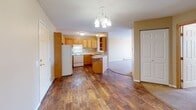 Located at 2321 Troop Dr in Sartell, Minnesota, this single-floor unit offers a well-designed layout that balances functionality and comfort. The kitchen is a standout feature, outfitted with warm oak cabinetry, ample upper and lower storage, a built-in wine rack with an arched display, a double sink, and white appliances including a range and refrigerator. Rich hardwood-style flooring runs throughout the kitchen and main living area, adding warmth and visual continuity. A chandelier above the entry area provides a welcoming touch as the space opens toward the kitchen. The living room is carpeted and features a corner gas fireplace with a light wood surround, creating a cozy focal point. An arched pass-through window connects the living room to the kitchen, enhancing the open feel between spaces. The bedrooms are carpeted with neutral-toned walls, baseboard heating, and natural light from windows with blinds. Two bathrooms serve the unit — one featuring a bold checkered tile floor with warm yellow walls, and the other with a matching checkered tile floor, oak vanity cabinetry, and a wide mirror. Textured ceilings are present throughout, and baseboard heating is a consistent feature across rooms.