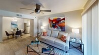 Located at 2311 E Union Hills Dr in Phoenix, AZ, this single-story residence offers a thoughtfully designed layout with modern finishes throughout. The open living room serves as the heart of the home, featuring wood-look flooring, a ceiling fan, and large sliding glass doors that invite natural light and provide access to an outdoor area. Bold, colorful wall art adds a vibrant touch to the neutral palette, while a glass-top coffee table and comfortable seating complete the space. The dining area sits adjacent to the kitchen and is anchored by a round glass-top table beneath a stylish pendant light fixture. The kitchen is equipped with stainless steel appliances — including a refrigerator, range, and dishwasher — white cabinetry, and light quartz-style countertops. A dedicated laundry area with a stacked washer and dryer is conveniently accessible from the kitchen. The bedroom is generously sized with plush carpet, a ceiling fan, and natural light from a window with blinds, offering a calm and restful retreat. Recessed accent lighting frames the bed wall for added ambiance. The bathroom includes a full tub and shower combination with chrome fixtures. Throughout the residence, a cohesive, contemporary aesthetic creates a comfortable and functional living environment.