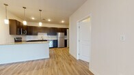This well-appointed single-floor residence offers a thoughtfully designed layout that blends modern finishes with functional living spaces. The open-concept kitchen serves as the centerpiece of the home, showcasing rich dark-espresso cabinetry, granite countertops, and a classic white subway tile backsplash. A full suite of stainless steel appliances — including a refrigerator, electric range, over-the-range microwave, and dishwasher — provides everything needed for everyday cooking. Pendant lighting above the kitchen island adds a stylish touch, while a dedicated pantry closet offers convenient additional storage. Light-toned hardwood-style flooring flows throughout the main living and kitchen areas, lending warmth and continuity to the space. The bedrooms are carpeted for comfort and feature ceiling fans, large windows with blinds that invite natural light, and ample room for furnishings. Each bedroom also provides access to closet space. The bathroom is finished with a full tub and shower combination surrounded by large-format white tile, a dark-cabineted vanity topped with granite, and wood-look flooring. Clean white walls and crisp trim throughout the residence create a bright, move-in-ready atmosphere that feels both modern and welcoming.