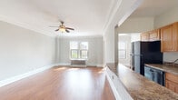 Situated along South Hyde Park Boulevard in Chicago's storied Hyde Park neighborhood, this single-floor residence combines classic architectural character with functional living spaces. Throughout the main living areas, warm hardwood floors and elegant crown molding establish a refined aesthetic, while ceiling fans and large windows allow ample natural light to fill the rooms. The spacious living room is anchored by a traditional cast-iron radiator and offers open views of the surrounding neighborhood.

The kitchen features wood cabinetry, granite-look countertops, a gas range, and a stainless steel refrigerator. A built-in china cabinet with glass-paned doors adds a charming, period-appropriate detail. A breakfast bar connects the kitchen to the living area, creating a practical and open flow between spaces.

The bedrooms are generously proportioned, with carpeted floors, crown molding, ceiling fans, and cast-iron radiators. One bedroom includes a mirrored sliding-door closet with built-in shelving. The bathroom is appointed with a full soaking tub, a handheld showerhead, tile wainscoting, and a window for natural ventilation. The overall layout, as seen in the dollhouse view, provides a well-organized and connected floor plan suited to comfortable everyday living.
