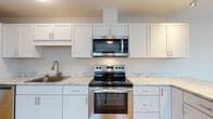 Located at 171 Scarborough Downs Road in Scarborough, Maine, this single-floor unit offers a clean, contemporary layout with thoughtful finishes throughout. The kitchen is a standout feature, equipped with stainless steel appliances including an electric range, over-the-range microwave, and dishwasher. Crisp white shaker-style cabinetry extends to the ceiling, complemented by light marble-patterned countertops and a stainless steel sink. Light wood-tone flooring runs through the kitchen and adjoining areas, lending warmth and continuity to the space. A peninsula-style counter extension provides additional prep space and opens to a bright dining or flex area with a window overlooking the exterior. The bedroom is finished with neutral-toned carpet and features multiple windows dressed with white blinds, allowing ample natural light to fill the room. Baseboard heating is present throughout, ensuring efficient climate control. The bathroom is finished with the same light wood-look tile flooring, offering a cohesive aesthetic, and includes a window that brings in natural light. The overall design palette is neutral and modern, with light walls and consistent finishes creating a bright, welcoming atmosphere throughout the unit.