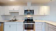 Located at 171 Scarborough Downs Road in Scarborough, Maine, this single-floor unit offers a clean, contemporary layout with thoughtful finishes throughout. The kitchen is a standout feature, equipped with stainless steel appliances including an electric range, over-the-range microwave, and dishwasher. Crisp white shaker-style cabinetry extends to the ceiling, complemented by light marble-patterned countertops and a stainless steel sink. Light wood-tone flooring runs through the kitchen and adjoining areas, lending warmth and continuity to the space. A peninsula-style counter extension provides additional prep space and opens to a bright dining or flex area with a window overlooking the exterior. The bedroom is finished with neutral-toned carpet and features multiple windows dressed with white blinds, allowing ample natural light to fill the room. Baseboard heating is present throughout, ensuring efficient climate control. The bathroom is finished with the same light wood-look tile flooring, offering a cohesive aesthetic, and includes a window that brings in natural light. The overall design palette is neutral and modern, with light walls and consistent finishes creating a bright, welcoming atmosphere throughout the unit.