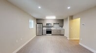 Located at 1053 Coleman Road in San Jose, California, this efficiently designed 580-square-foot, single-story unit offers 1 bedroom and 1 bathroom with a clean, modern aesthetic. Light wood-tone vinyl plank flooring runs throughout, complementing the neutral beige and white walls that give the space a bright, cohesive feel.

The kitchen is a standout feature, outfitted with contemporary gray-toned cabinetry, white quartz countertops, and a subtle glass subway tile backsplash. A full suite of stainless steel appliances includes a refrigerator, range, over-the-range microwave, and dishwasher, making this kitchen both functional and stylish.

The 150-square-foot bedroom receives natural light through a window overlooking greenery and is equipped with a wall-mounted mini-split HVAC unit for individualized climate control. An adjacent walk-in closet features wrap-around hanging rods and open shelving for ample storage.

The bathroom is finished in a modern style with a floating wood-tone vanity, white countertop, large mirror, and a glass-enclosed walk-in shower with white tile surround. A hallway connects the main living areas, completing this well-organized floor plan. The unit's contemporary design and efficient layout make it a practical and attractive living space.