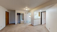 Located at 1808 Visscher Dr in Elkhart, Indiana, this single-floor unit offers a practical and functional layout designed for comfortable everyday living. The living area is generously sized, finished with neutral wall-to-wall carpeting and topped with a textured ceiling. A sliding glass door with vertical blinds floods the space with natural light and provides direct access to an outdoor patio, offering views of the surrounding greenery.

The galley-style kitchen is positioned adjacent to the living area and accessible via a pass-through counter, creating an open connection between the two spaces. It features light-toned cabinetry with wood-trimmed detailing, white appliances including a full-size refrigerator and range, and tile flooring that contrasts with the carpeted areas throughout the rest of the unit.

The bedroom is a well-proportioned room with soft carpeting, a window that allows natural light to filter in, and a closet with bifold doors providing ample storage. A dedicated bathroom is accessible from the bedroom area, completing the private quarters of the unit. Sliding mirrored closet doors near the living space add depth and functionality. Overall, the unit presents a clean, neutral palette throughout.