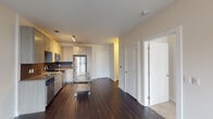 Located at 530 Foster St in the heart of Durham, NC, this single-floor residence offers a thoughtfully designed layout with modern finishes and a clean, contemporary aesthetic. The kitchen is a standout feature, showcasing light wood cabinetry that extends to the ceiling for generous storage, a textured tile backsplash, granite countertops, and a full suite of stainless steel appliances including a refrigerator, range, microwave, and dishwasher. Rich, dark hardwood flooring grounds the kitchen and open living area, creating a warm contrast against the neutral walls and white trim. The living space flows naturally from the kitchen, offering an open and versatile layout ideal for a variety of arrangements. The bedroom is finished with plush wall-to-wall carpet, a ceiling fan with light fixture, and a large window that invites natural light and views of the surrounding neighborhood. An additional carpeted room provides flexible use as a secondary bedroom or office space. The bathroom features a granite-topped vanity with an undermount sink, modern wood-toned cabinetry, and a large mirror, complementing the overall design language of the residence. Multiple closets throughout the unit offer practical storage solutions. The space combines functional design with quality materials for comfortable urban living in downtown Durham.