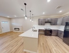 This 840 square foot residence, located at Foxglove ADA, offers a thoughtfully designed single-floor layout optimized for accessibility and modern living. The home comprises one bedroom, one bathroom, a combined kitchen and living room area, two hallways, and a dedicated laundry space. The primary bedroom, measuring 180 square feet, provides ample space and features a ceiling fan for comfort.

The open-concept living area is the heart of the home, showcasing a sleek electric fireplace that serves as a focal point. Beautiful hardwood flooring extends throughout, creating a cohesive and warm ambiance. The kitchen boasts modern gray cabinetry, contrasting nicely with white countertops and backsplash. Black appliances, including a refrigerator and range, complete the contemporary aesthetic.

The bathroom is designed with accessibility in mind, featuring grab bars, a spacious layout, and a floating vanity. The laundry room is equipped with a full-sized washer and dryer, ensuring convenience for daily tasks. Recessed lighting throughout the home provides even illumination, while windows allow natural light to flood the spaces.

ADA considerations are evident in the wide doorways, lever-style door handles, and overall spacious design that allows for easy maneuverability. The neutral color palette and clean lines contribute to a modern, inviting atmosphere, making this compact home both functional and stylish.