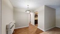 This single-floor residence offers a well-organized layout with a comfortable and functional design throughout. The living area welcomes you with plush carpeting, neutral beige walls, and a textured ceiling, creating a warm and inviting atmosphere. A pendant light fixture anchors the dining area, which transitions seamlessly into the hardwood-style flooring that extends through the main traffic areas. French doors in the living space open to a private balcony, allowing natural light to filter in and providing an easy indoor-outdoor connection. A wall-mounted HVAC unit ensures year-round comfort.

The kitchen is a standout feature, showcasing dark cabinetry paired with a striking mosaic tile backsplash in earthy tones of brown, beige, and cream. Light stone-finish countertops and a black electric range with an overhead vent hood complete the space, offering both style and practicality.

The bedroom is generously sized, fitted with soft carpeting, a ceiling fan with light fixture, and a window with blinds that brings in pleasant natural light. A walk-in closet provides ample storage. The bathroom is clean and straightforward, featuring a full tub-shower combination, hardwood-style flooring, and a vanity with matching countertops. White trim and doors throughout the unit lend a cohesive, polished finish.
