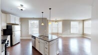 Located at 3280 Centennial Ridge in Grand Rapids, Michigan, this single-story home presents a cohesive, neutral design palette complemented by warm hardwood flooring that extends throughout the main living areas. The open-concept layout connects the kitchen, dining, and living spaces seamlessly, creating a bright and airy atmosphere enhanced by multiple windows that draw in generous natural light.

The kitchen is a functional centerpiece, featuring crisp white cabinetry with dark hardware, a tile backsplash, dark countertops, and a full suite of stainless steel appliances including a gas range, over-the-range microwave, and refrigerator. A central island with a built-in sink and pendant lighting above serves as both a prep area and casual gathering spot. The adjacent dining area benefits from a bay window arrangement and a chandelier overhead, while a secondary dining or living space offers additional windowed views and direct access to the exterior.

Bedrooms are finished with plush neutral carpet and windows that allow ample daylight. The bathrooms are finished in coordinating neutral tones, featuring undermount sinks, light cabinetry, and walk-in shower options. Throughout the home, clean white trim, consistent warm-taupe wall colors, and thoughtful lighting fixtures contribute to a polished, move-in-ready aesthetic.