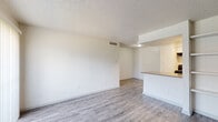 Located at 12000 Fleming Dr in Houston, TX, this 1-bedroom, 2-bathroom unit offers a thoughtfully designed single-floor layout. The open-concept living and dining area is bright and airy, featuring wood-look luxury vinyl flooring, a textured ceiling, and a sliding glass door that floods the space with natural light and leads out to a private patio. The kitchen is outfitted with white cabinetry, a sleek gray-topped peninsula with an integrated sink, black appliances including a refrigerator and range, and overhead lighting — all flowing seamlessly into the dining and living spaces. The bedroom is a comfortable retreat with a ceiling fan, a window offering outdoor views, and a dedicated closet with double doors for ample storage. The two bathrooms are clean and functional: one features a tub-shower combination with tile surround and overhead cabinet storage, while the other includes a wide vanity with a white basin sink, brushed nickel fixtures, and a mirrored medicine cabinet. Consistent wood-look flooring runs through both bathrooms, tying the unit together. Neutral white walls and an efficient, well-organized floor plan make this a practical and move-in-ready space.