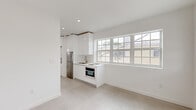 Located at 659 Meridian Ave in the heart of Miami Beach, FL, this compact yet well-designed one-bedroom, one-bathroom unit offers a clean, modern aesthetic throughout. The interior is defined by a consistent all-white palette, light-toned large-format tile flooring, and recessed lighting that enhances the bright, airy atmosphere.

The open living and kitchen area is anchored by a sleek, modern kitchen featuring high-gloss white cabinetry extending floor to ceiling, a stainless steel refrigerator, an induction cooktop, a built-in oven, and a single-basin sink. A wide bank of multi-pane windows floods the space with natural light and provides views of the surrounding Miami Beach neighborhood, creating a seamless connection between interior and exterior.

The bedroom is a well-proportioned, tranquil retreat featuring two windows that frame lush tropical foliage outside, a sliding closet, and a wall-mounted split air conditioning unit for efficient climate control. The light tile flooring reflects natural light, enhancing the sense of openness.

The bathroom is finished in the same clean, minimalist style, with a floating white vanity accented by brushed gold hardware, a mirror, and a glass-panel door adding a refined touch to the compact space.