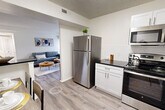Located at 7931 Patriot Drive in Annandale, Virginia, this two-bedroom, one-bathroom residence offers a thoughtfully designed single-floor layout with a bright, open feel throughout. The kitchen is a standout feature, outfitted with crisp white shaker cabinetry, dark granite countertops, a white subway tile backsplash, and a full suite of stainless steel appliances including a refrigerator, range, microwave, and dishwasher. Light wood-style flooring extends through the kitchen, dining, and living areas, creating a cohesive and clean aesthetic. The living room is generously proportioned, bathed in natural light from large sliding glass doors that open directly onto a private balcony with outdoor views. The primary bedroom is spacious, featuring plush carpeting, dual louvered closets, and convenient access to the shared bathroom. The second bedroom also offers carpeted flooring and closet space. The bathroom is well-appointed with white cabinetry, dark granite countertops, and wood-style flooring. With six closets spread across the unit, storage is abundant. A dedicated hallway and entrance area complete the efficient floor plan, making this a well-organized and comfortable residence.