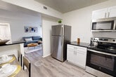 Located at 7931 Patriot Drive in Annandale, Virginia, this two-bedroom, one-bathroom residence offers a thoughtfully designed single-floor layout with a bright, open feel throughout. The kitchen is a standout feature, outfitted with crisp white shaker cabinetry, dark granite countertops, a white subway tile backsplash, and a full suite of stainless steel appliances including a refrigerator, range, microwave, and dishwasher. Light wood-style flooring extends through the kitchen, dining, and living areas, creating a cohesive and clean aesthetic. The living room is generously proportioned, bathed in natural light from large sliding glass doors that open directly onto a private balcony with outdoor views. The primary bedroom is spacious, featuring plush carpeting, dual louvered closets, and convenient access to the shared bathroom. The second bedroom also offers carpeted flooring and closet space. The bathroom is well-appointed with white cabinetry, dark granite countertops, and wood-style flooring. With six closets spread across the unit, storage is abundant. A dedicated hallway and entrance area complete the efficient floor plan, making this a well-organized and comfortable residence.