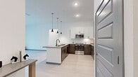 Located in Apollo Beach, Florida, this well-appointed single-story residence offers five bedrooms and two full bathrooms across a thoughtfully designed floor plan. The modern kitchen is a standout feature, showcasing a large central island with a built-in sink and matte black faucet, sleek quartz countertops, white upper cabinetry paired with rich dark lower cabinets, a white subway tile backsplash, and a full suite of stainless steel appliances including a refrigerator, range, and microwave. Pendant lighting above the island adds a contemporary touch, while light wood-look flooring extends throughout the main living areas. The five bedrooms are carpeted for comfort, each offering closet storage and natural light from windows dressed with blinds. The spacious primary bedroom includes a dedicated walk-in closet with built-in wire shelving. The two bathrooms are finished with clean, modern fixtures — one features a tiled tub-shower combo, while the other boasts a frameless glass walk-in shower with a rain-style showerhead and tiled surround. Both include vanities with dark cabinetry and stone-topped counters. The home's neutral color palette and consistent finishes throughout create a cohesive, contemporary ambiance.