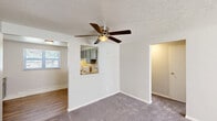Located at 3 Marhoefer Drive in Pleasant Hills, PA, this two-bedroom, one-bathroom residence offers a practical and comfortable single-floor layout. The living area features plush wall-to-wall carpeting, a textured ceiling, and a ceiling fan with integrated lighting. A pass-through window connects the living space to the kitchen, which is equipped with gray cabinetry, a sink, and essential appliances, allowing for an open sightline between the two areas. Hardwood-style flooring is present in the kitchen and hallway, providing a clean contrast to the carpeted rooms. The spacious primary bedroom is generously proportioned, featuring a ceiling fan, a large window with blinds that allows ample natural light, and a baseboard heating unit. The second bedroom is similarly appointed with carpet, a ceiling fan, a window, and a closet with a hanging rod. Both bedrooms benefit from natural light and include individual climate control units. The full bathroom is finished with classic white subway tile surrounding a shower and tub combination, complemented by a window for natural ventilation. A hallway connects the main living areas, with a closet providing convenient additional storage near the entryway.