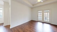 This well-appointed 2-bedroom, 1-bathroom single-floor home at 150 Du Rhu Dr in Mobile, Alabama offers a thoughtful layout across a comfortable footprint. The living room is a standout space, featuring rich hardwood-style flooring, crown molding, a tray ceiling with a ceiling fan, and a classic fireplace framed by a clean white surround — all complemented by a glass-paneled door that invites natural light and outdoor views. Adjacent to the living area, the dining room continues the hardwood-style flooring and is illuminated by an elegant chandelier, with a bank of large windows offering neighborhood views. The kitchen is outfitted with white cabinetry, granite-look countertops, light tile flooring, and a full suite of white appliances including a gas range. Both bedrooms are carpeted and offer a calm, neutral palette; the primary bedroom includes a ceiling fan and a door leading to the exterior. The full bathroom features tile flooring, a tub-shower combination, and a vanity with ample storage. A dedicated laundry room with built-in shelving and a separate closet round out the practical amenities of this functional and inviting home.