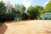 Located at 1008 Cherokee Road in Portsmouth, Virginia, this single-story facility is designed to serve as a welcoming community space. The exterior is constructed of classic red brick, complemented by a well-maintained outdoor area that includes a colorful teal and yellow metal climbing structure set over a wood chip safety surface — ideal for recreational use. Mature trees provide natural shade around the grounds, enhancing the outdoor environment.

Inside, the entryway greets visitors with warm, neutral-toned walls and durable slate-style tile flooring in earthy hues that carry throughout the entrance corridor. The transition area is thoughtfully appointed with glass-paneled doors that allow natural light to filter in and provide clear sightlines into the adjoining interior spaces. A framed nautical photograph of a sailboat on calm water adds a local coastal character to the entry hall, nodding to Portsmouth's maritime heritage.

The interior common areas, visible through the glass doors, feature ceiling fans, light tile flooring, and a bright, open atmosphere. The space is equipped with standard safety infrastructure, including a clearly mounted fire alarm pull station. Clean white trim and panel-style doors throughout contribute to a tidy, functional aesthetic. Overall, the facility presents a practical yet pleasant environment suited for community gatherings and programs.