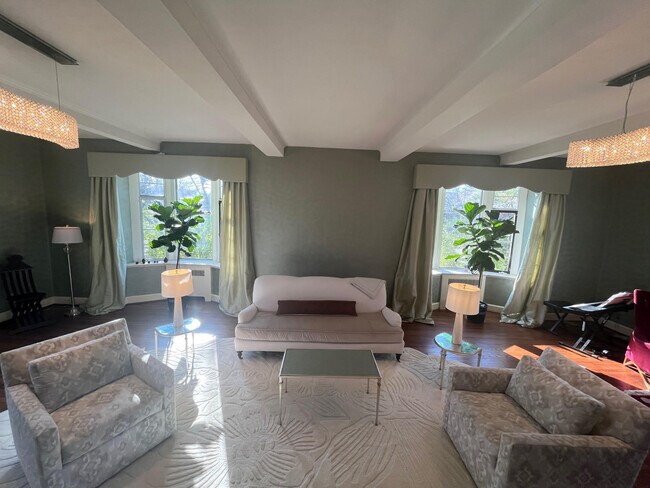 Sala de estar formal con ventanas en tres lados y techo con vigas. - 5553 Little Falls Rd