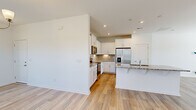 Located on Barwell Drive in Charlotte, NC, this two-story home offers a well-organized layout across two floors, with three bedrooms and three full bathrooms. The main level hosts an open-concept kitchen and living area, highlighted by light hardwood-style flooring, recessed lighting, and a clean, neutral color palette. The kitchen is equipped with white shaker cabinetry, granite countertops, stainless steel appliances including a French door refrigerator and range, a tile backsplash, and a central island with a sink — ideal for both meal prep and casual dining. The living area flows naturally from the kitchen, featuring large windows that invite natural light and neighborhood views. An attached garage with an automatic door opener and a dedicated utility room add practical convenience on the ground floor. Upstairs, the three bedrooms are carpeted for comfort, each with access to natural light through well-placed windows. The spacious primary bedroom includes a closet and direct access to a bathroom. Additional bedrooms share a full bathroom featuring a tub-shower combination, white vanity, and wood-look tile flooring. A second staircase configuration enhances the home's functional flow. The exterior includes a concrete driveway and landscaped grounds.