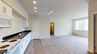 This single-floor residential unit offers a clean, functional layout with a neutral color palette and quality finishes throughout. The open-concept kitchen and living area serves as the heart of the unit, featuring wood-look hard flooring in the kitchen zone that transitions seamlessly into plush carpet in the living space. The kitchen is well-equipped with white cabinetry, dark countertops, white appliances including a refrigerator, electric range, built-in microwave, and dishwasher, all illuminated by a track lighting system overhead. A door off the kitchen provides additional access to the unit.

The generously sized living area benefits from natural light through a glass-paneled door that opens to a private balcony with outdoor views. The bedrooms are carpeted and fitted with ceiling fans, baseboard heaters, and windows that bring in natural light. One bedroom includes direct access to a walk-in closet with wire shelving for ample storage.

The bathrooms are well-appointed, with one featuring a wide vanity with dark countertops, a large mirror with overhead lighting, and built-in shelving, while another includes a sleek frameless glass sliding shower enclosure. The unit combines practical storage solutions with a bright, move-in-ready aesthetic throughout.