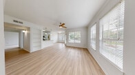 This single-floor home offers a clean, modern aesthetic highlighted by light wood-style flooring, crisp white walls, and crown molding throughout the main living areas. The open-concept living and dining space is generously proportioned, bathed in natural light from large windows dressed with white blinds, and anchored by a ceiling fan overhead. A built-in shelving unit adds a functional decorative touch, while a seamless sightline connects the living area to the kitchen.

The kitchen is well-equipped with stainless steel appliances, including a range and over-the-range microwave, complemented by granite countertops, a subway tile backsplash, and gray-toned cabinetry. An adjacent dining nook with a window provides a bright, casual eating area. A dedicated laundry room just off the kitchen houses a full-sized washer and dryer.

The bedrooms feature plush carpeting, ceiling fans, and ample natural light. The primary suite includes a spacious walk-in closet outfitted with wire shelving and hanging rods on multiple walls. The bathrooms are finished with granite-topped vanities, sage-toned cabinetry with brushed hardware, and tub-shower combinations, offering a cohesive and polished look throughout.