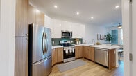 Located at 2001 Dabney Rd in Richmond, Virginia, this thoughtfully designed one-bedroom, one-bathroom unit offers a efficient and modern living experience across a single floor. The open-concept kitchen and living area anchors the space, featuring a contemporary kitchen outfitted with stainless steel appliances — including a French door refrigerator, gas range, and dishwasher — complemented by two-tone cabinetry with warm wood lower cabinets and crisp white uppers. A green tile backsplash adds a distinctive design accent, while light quartz countertops and a peninsula with bar seating create a seamless transition into the living and dining area. Light hardwood flooring flows throughout, enhancing the bright, airy atmosphere. The living room benefits from natural light streaming through multiple windows fitted with horizontal blinds, and is equipped with a ceiling fan. The bedroom is a calm retreat with a ceiling fan, a window, and a stylish barn-style sliding door leading to the closet. The bathroom features a full tub-shower combination with brushed nickel fixtures and stone tile flooring. Recessed lighting and clean white walls unify the space with a modern, cohesive aesthetic.