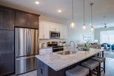 This two-floor home offers a thoughtfully designed open-concept layout that seamlessly connects the kitchen, dining, and living areas on the main level. The kitchen serves as a central hub, featuring an expansive granite-topped island with bar seating illuminated by elegant glass pendant lights. White shaker cabinetry, a subway tile backsplash, and a full suite of stainless steel appliances—including a gas range, built-in microwave, dishwasher, and refrigerator—complete the space. Light hardwood-style flooring runs throughout the main level, enhancing the bright, airy atmosphere.

The living room is a comfortable gathering space with a ceiling fan, recessed lighting, and large windows that invite natural light. A convenient powder room with granite countertops and wood-tone flooring is also located on the main level.

Upstairs, the bedrooms are finished with plush carpeting and neutral tones, offering a calm and restful environment. Each bedroom benefits from generous window placement. The full bathroom features a wide granite vanity, a wood-framed mirror, white cabinetry with brushed nickel hardware, and a walk-in shower, delivering a clean and polished aesthetic throughout.