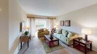 This single-floor residence offers a thoughtfully organized layout with distinct living, dining, sleeping, and kitchen areas. The living room is generously proportioned, featuring plush wall-to-wall carpeting, large sliding windows with sheer curtains that invite natural light, and ample space for multiple seating arrangements. Adjacent to the living area, the formal dining room accommodates a full-sized table for six beneath a decorative pendant light fixture, with a sliding closet providing additional storage.

The kitchen is functionally designed with warm-toned wood cabinetry, dark granite-style countertops, and black appliances including a gas range, dishwasher, and refrigerator. A window above the sink provides natural light and outdoor views.

The bedrooms are carpeted and comfortably sized, offering generous closet space. One bedroom connects directly to a bathroom, which features tile-surround tub and shower combination. A second bathroom includes a wide vanity with an extended countertop, large mirror, and bright Hollywood-style lighting. Neutral warm tones carry throughout the residence, creating a cohesive and welcoming ambiance in every room.