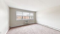 Located at 2 S Glenwood Ave in Clifton Heights, PA, this 3-bedroom, 1-bathroom unit offers a functional single-floor layout connecting all living spaces through a central hallway. The spacious primary bedroom is notably generous in size, featuring soft carpeting, dual louvered bi-fold closets providing ample storage, and a wall-unit air conditioner alongside baseboard heating. Large windows invite natural light and offer views of the surrounding neighborhood. The two additional bedrooms are also carpeted and well-lit, each with windows and baseboard heating. The kitchen features wood-look tile flooring, warm-toned cabinetry, a tiled backsplash, and includes a white electric range with an over-the-range microwave. The bathroom is clean and classic, showcasing white subway tile surrounding a full soaking tub with a shower, complemented by a vanity with storage below. Neutral gray-beige tones throughout the unit create a cohesive, move-in-ready aesthetic. The hallway efficiently connects all rooms, keeping the layout organized and accessible. This unit offers a practical and comfortable living environment in a residential Clifton Heights neighborhood.