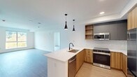 This contemporary 960 square foot apartment offers a thoughtful blend of style and functionality. The open-concept living area seamlessly integrates the kitchen, dining, and living spaces, creating an airy and inviting atmosphere. The kitchen boasts modern wood cabinetry, stainless steel appliances, and a convenient island with pendant lighting.

Both bedrooms are generously sized, with the primary bedroom measuring 190 square feet. Large windows in the bedrooms provide ample natural light and picturesque forest views. The two bathrooms feature sleek designs with wood vanities, illuminated mirrors, and modern fixtures.

Throughout the apartment, light-toned wood flooring complements the crisp white walls, enhancing the space's bright and open feel. A balcony accessible from one of the rooms offers a private outdoor retreat with scenic vistas.

Additional amenities include a ceiling fan for improved air circulation, built-in closets for ample storage, and a separate laundry area. The apartment's layout efficiently utilizes the available space, making it an ideal choice for those seeking a contemporary living environment with all the essentials for comfortable urban living.