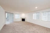 This single-floor residential unit offers a practical and comfortable layout designed for everyday living. A central hallway connects the main areas of the home, providing a clear sense of flow from entry to living spaces.

The living room serves as the heart of the unit, featuring plush wall-to-wall carpeting, a tile-surround fireplace as a focal point, and a large sliding glass door flanked by vertical blinds that invite natural light and provide access to an outdoor area. An adjacent window further brightens the space.

The kitchen is efficiently laid out with light wood cabinetry, laminate countertops, a double stainless steel sink, and tile flooring. A full-size refrigerator and stovetop are included, making the space fully functional.

The bedrooms are carpeted and well-lit, each featuring windows with blinds that allow for natural light and privacy. One bedroom includes a baseboard heater, while another benefits from convenient proximity to the bathroom.

The bathrooms are finished with light wood vanity cabinetry, laminate countertops, single-basin sinks, large mirrors with overhead lighting, and tile flooring — offering a clean and practical aesthetic throughout.

Overall, the unit presents a neutral, move-in-ready palette with consistent finishes and ample natural light across all rooms.