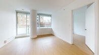 Located at 1051 Broughton Street in Vancouver's vibrant West End neighbourhood, this well-appointed three-bedroom, two-bathroom unit offers a practical and modern layout across a single floor. Light bamboo hardwood flooring flows throughout the main living areas and bedrooms, lending warmth and continuity to the space.

The kitchen is thoughtfully designed with two-tone cabinetry — white upper cabinets paired with grey lower units — complemented by a textured tile backsplash and a full suite of stainless steel appliances including a refrigerator, range, and built-in microwave. Track lighting and a pendant fixture illuminate the workspace efficiently.

The living area is bright and open, featuring floor-to-ceiling windows that frame views of the surrounding West End streetscape and greenery, with a distinctive round column adding an architectural accent. Natural light fills the room throughout the day.

The three bedrooms are clean and versatile, with white walls and continued bamboo flooring. The primary bedroom offers a comfortable footprint suited for a full bedroom set. The two bathrooms are finished in a modern style — one featuring large-format tile flooring, white subway tile surrounding a soaker tub, and chrome fixtures; the second offering a more compact, functional design with granite countertop detailing.