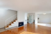 Located on Westwood Boulevard in Los Angeles, this two-bedroom, two-bathroom home spans two floors, offering a well-organized and functional layout. The main floor hosts a bright, open-concept living and dining area finished with warm hardwood flooring that flows throughout. A classic fireplace with a granite surround anchors the living room, while a staircase with wood treads and white railings connects to the upper level. Sliding glass doors lead to a private balcony, filling the space with natural light and outdoor views. The galley-style kitchen features white cabinetry, granite countertops, a mosaic tile backsplash, stainless steel appliances including a gas range, and tile flooring. Frosted glass interior doors add a modern touch to the lower level. Upstairs, two well-sized bedrooms each feature hardwood floors, large windows, and wall-unit climate control. The spacious primary bedroom includes a built-in vanity with storage drawers and a mirrored closet. Both bathrooms are finished with granite countertops, tile flooring, and tub-shower combinations. Throughout the home, bright white walls and textured ceilings maintain a clean, airy aesthetic consistent with the sunny Los Angeles setting.