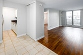 This one-bedroom, one-bathroom unit at 100 Ferguson Avenue South in Hamilton offers a efficiently designed layout across a single floor. The living room is a welcoming space featuring wood-look laminate flooring and large sliding glass doors that open to a private balcony, allowing natural light to fill the room and providing views of the surrounding neighbourhood. The transition from the entryway, finished with light ceramic tile, to the living area is clearly defined by the flooring change.

The kitchen is thoughtfully appointed with dark granite countertops, white cabinetry with brushed steel hardware, and an electric stove, offering a clean, functional workspace. The bedroom features the same warm wood-look flooring, a window with neighbourhood views, and a built-in sliding-door closet providing practical storage. A textured ceiling is consistent throughout the unit.

The bathroom is finished in a crisp white palette, featuring a tub-shower combination with classic white subway tile accented by a decorative mosaic border, a white vanity with a light countertop, and tile flooring. Clean lines and neutral tones throughout the unit create a cohesive, move-in ready living environment.