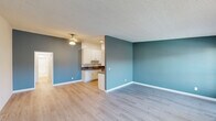 This 2-bedroom, 1-bathroom single-floor residence offers a practical and comfortable layout with a clean, modern aesthetic throughout. Light-toned hardwood-style flooring runs continuously across the living areas and bedrooms, creating a cohesive and bright interior. The open living and kitchen area serves as the heart of the home, featuring a bold teal accent wall that adds a pop of color to the otherwise neutral palette. Textured ceilings and a ceiling fan complete the living space.

The galley-style kitchen is efficiently designed with ample white cabinetry, gray countertops, a stainless steel refrigerator, a range, and a dishwasher — providing generous storage and functionality in a compact footprint. A dedicated overhead light keeps the space well-lit.

Both bedrooms are generously proportioned with neutral walls, light flooring, and wall-unit air conditioning. The spacious primary bedroom features large windows that allow natural light to filter in. The second bedroom connects conveniently to the main living area.

The bathroom is clean and bright, featuring a tub-shower combination enclosed by a sleek sliding glass door with chrome fixtures and a window for natural ventilation. Throughout the residence, white trim and baseboards provide a crisp finishing touch, lending the space a tidy and well-maintained character.