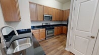 This 630 square foot, one-bedroom apartment in Herndon, VA offers a well-designed living space on a single floor. The open-concept layout seamlessly integrates the kitchen and living room, creating a spacious feel. The kitchen boasts modern stainless steel appliances, including a gas range and microwave, complemented by ample wood cabinetry and dark countertops. Hardwood flooring extends throughout the main living areas, adding warmth and elegance.

The bedroom, measuring 150 square feet, features plush carpeting and a large window with an arched top, allowing natural light to flood the space. A walk-in closet provides generous storage. The bathroom is equipped with a single vanity, toilet, and likely a shower or tub (not visible in images).

Large windows in the living area offer views of the surrounding greenery, enhancing the apartment's bright and airy ambiance. Track lighting in the living room and recessed lighting in the kitchen provide ample illumination. The neutral color palette of white walls and light carpeting in the bedroom creates a blank canvas for personalization. This apartment combines functionality with modern aesthetics, ideal for comfortable urban living.