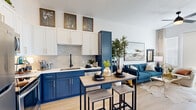 Located at Sapphire Falls in Colorado Springs, CO, this one-bedroom, one-bathroom residence offers a thoughtfully designed open-concept layout that maximizes every square foot. Light-toned hardwood flooring flows throughout, tying together each functional area seamlessly.

The kitchen is a standout feature, showcasing bold navy-blue lower cabinetry contrasted by crisp white upper cabinets, a geometric hexagonal tile backsplash, black matte fixtures, and stainless steel appliances. A freestanding bar-height island provides additional prep space and casual dining.

The kitchen opens directly into the living room, which benefits from abundant natural light streaming through a sliding glass door that leads to a private balcony overlooking the surrounding community. A ceiling fan adds comfort to the airy space.

The bedroom is a well-proportioned retreat featuring a large window that frames views of the neighborhood and distant terrain, with light-filtering blinds and elegant draping curtains enhancing the serene atmosphere.

The bathroom is cleanly finished with wood-look tile, a tub-shower combination with matte black hardware, and classic white fixtures, completing this well-appointed Colorado Springs residence.