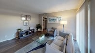 Located at 2424 N Tustin Ave in Santa Ana, California, this single-floor residence offers a thoughtfully designed layout with modern updates throughout. The kitchen is a functional and attractive space, featuring dark espresso cabinetry, a white subway tile backsplash, light quartz countertops, stainless steel appliances, and a window with natural light streaming through slatted blinds. The dining area accommodates a full-sized table and chairs beneath a ceiling fan, with a decorative circular mirror adding visual interest to the neutral-toned walls and dark hardwood-style flooring. The living room is open and inviting, with sliding glass doors that allow ample natural light and connect to an outdoor area. Dark hardwood-style floors continue through the main living spaces, complementing the neutral color palette. A dedicated office or den area offers carpeted flooring, a window with garden views, and a quiet retreat for work or relaxation. The bedroom is a standout, featuring a striking multi-toned reclaimed wood accent wall that brings warmth and character to the space, paired with plush carpeting. The bathroom showcases a vessel sink atop a quartz vanity surface, framed by a dark-bordered mirror, delivering a clean and contemporary aesthetic throughout.