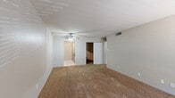This single-floor unit offers a practical and comfortable layout across several well-defined living spaces. The main living area is generously sized, finished with warm beige wall-to-wall carpeting and neutral-toned walls that create a bright, open atmosphere. A ceiling fan with a light fixture provides both comfort and illumination. A dedicated entry door leads directly into this space, and openings connect it to the rest of the unit.

The galley-style kitchen is efficiently designed with gray cabinetry lining both sides, laminate countertops, tile flooring, and a full suite of appliances including a refrigerator, dishwasher, and range. A stainless steel double sink sits beneath a practical workspace, making the kitchen well-equipped for everyday use.

The bedrooms are carpeted and feature neutral walls, ceiling fans, and closet access. One bedroom includes a window that allows natural light to filter in. A sliding panel door leads to an additional room or closet area, adding to the overall storage capacity of the unit. A walk-in style closet with built-in hanging rods provides ample wardrobe storage.

The bathroom is clean and functional, featuring a full tub-shower combination, a toilet, a vanity with a speckled countertop, and tile flooring throughout. Overall, this unit offers a straightforward, move-in-ready layout suited for comfortable everyday living.
