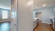 Located at 646 W Smith St in Orlando, FL, this single-story unit offers a thoughtfully designed layout with modern finishes and a cohesive soft blue-gray color palette throughout. The open-concept kitchen is a standout feature, equipped with stainless steel appliances including a refrigerator, electric range, and over-the-range microwave. Gray shaker-style cabinetry, white quartz countertops, a classic subway tile backsplash, and wood-look vinyl flooring complete the kitchen's contemporary aesthetic. A kitchen island with a built-in sink and pendant lighting adds both functionality and style, flowing seamlessly into the living and dining areas. The living area is generously sized, featuring wood-look flooring, a ceiling fan, and multiple windows fitted with horizontal blinds that allow for ample natural light. The bedrooms are carpeted for comfort, each offering windows with views of the surrounding greenery and ceiling fans for climate control. The bathrooms are finished with wood-look tile flooring, white subway-tiled tub/shower surrounds, light blue vanity cabinetry, white countertops, and large mirrors. Panel-style interior doors and crisp white baseboards add a clean, polished look throughout the entire space.