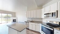 Located at 535 Hickory Street in Wrightstown, Wisconsin, this one-bedroom, one-bathroom unit offers a thoughtfully designed single-floor layout with modern finishes throughout. The open-concept kitchen and living area serves as the heart of the space, where the kitchen impresses with crisp white shaker cabinetry, granite countertops, a large center island, and a full suite of stainless steel appliances including a French door refrigerator, electric range, built-in microwave, and dishwasher. An in-unit washer and dryer are conveniently tucked behind closed doors near the kitchen. The living room features light wood-tone flooring, a corner fireplace, and expansive sliding glass doors that flood the space with natural light and frame picturesque waterfront views. The bedroom continues the waterfront theme with a large window overlooking the water, a ceiling fan, and access to a generously sized walk-in closet outfitted with wire shelving. The bathroom offers a dual-sink vanity with granite countertops, white cabinetry, and a large mirror, maintaining the clean, contemporary aesthetic found throughout the unit. Light, neutral tones and durable flooring tie the entire space together cohesively.