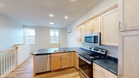 Located at 1 Manseau St, Unit B in Winooski, Vermont, this two-floor residence offers a thoughtfully designed layout spread across two levels. The main floor showcases a contemporary kitchen fitted with light maple cabinetry, dark countertops, and a full suite of stainless steel appliances, including a range, microwave, dishwasher, and refrigerator. A peninsula with an integrated sink adds both prep space and an open connection to the living area. Light hardwood flooring runs throughout this level, complemented by recessed lighting and natural light from double windows that overlook the outdoors. A convenient half bathroom on this floor features matching light wood cabinetry and hardwood-style flooring. The upper floor transitions to soft carpet and includes a spacious bedroom area with a wall-mounted mini-split system for efficient heating and cooling. A stacked washer and dryer unit is neatly tucked into a dedicated nook, adding everyday convenience. Two closets provide ample storage, and a full bathroom serves the upper level. Hallways on both floors connect the spaces smoothly, and a staircase links the two levels. The overall design is clean and modern, with a neutral palette throughout that creates a bright, functional living environment.