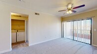 This thoughtfully laid-out one-bedroom, one-bathroom residence offers a comfortable and efficient use of space across a single floor. The open-concept kitchen and living area forms the heart of the home, with the living room featuring soft carpet flooring, crown molding, a ceiling fan with light fixture, and sliding glass doors that lead to a private balcony, filling the space with natural light. The kitchen is well-appointed with light wood cabinetry, dark granite-style countertops, hexagonal tile flooring, recessed lighting, and a full suite of stainless steel appliances including a gas range, microwave, dishwasher, and refrigerator. The bedroom is a comfortable retreat with plush carpet, a ceiling fan, and a window fitted with vertical blinds for light control and privacy. The bathroom mirrors the kitchen's modern aesthetic, featuring a wood-toned vanity with a dark stone countertop, hexagonal tile flooring, a large mirror, and a tub-shower combination. A dedicated in-unit laundry area with a full-size washer and dryer and overhead shelving adds everyday convenience. A separate closet provides additional storage, rounding out the practical and cohesive design of this residence.
