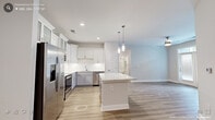 This single-story residence in Wake Forest, NC offers a thoughtfully designed layout with clean, contemporary finishes throughout. Light hardwood-style flooring runs consistently across all areas, creating a cohesive and warm aesthetic from room to room.

The kitchen serves as a standout feature, equipped with stainless steel appliances, white shaker-style upper cabinets with glass inserts, gray lower cabinets, a white subway tile backsplash, and a granite-topped center island illuminated by pendant lighting. Ample counter space and recessed lighting complete this well-appointed cooking space.

The living area includes a set of French doors topped with a transom window, inviting abundant natural light and providing outdoor access. Individual rooms feature ceiling fans with light fixtures and windows dressed with blinds.

Two full bathrooms offer granite-topped vanities, white cabinetry, and hardwood-style flooring. One includes a tub-shower combination, while the other features a glass-enclosed shower. A dedicated laundry area houses a full-size washer and dryer with overhead wire shelving. Walk-in closet space with wire shelving systems provides generous storage. The overall design is clean, neutral, and move-in ready.