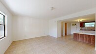 Located at 8570 W Mayo Dr in Crystal River, Florida, this single-floor unit offers a straightforward and functional layout designed for efficient use of space. Light-toned ceramic tile flooring runs throughout the entire unit, providing a clean, cohesive look that is easy to maintain.

The open-concept kitchen and living area forms the heart of the unit. The living space features white walls and ample natural light streaming in through windows, creating a bright and airy atmosphere. The kitchen is well-equipped with warm wood-toned upper and lower cabinetry, white lower base cabinets, a double sink, a white refrigerator, a four-burner electric range with oven, and generous counter space along a peninsula that separates the kitchen from the living area. A wall-mounted air conditioning unit provides climate control.

A secondary kitchen area includes additional cabinetry and counter space, offering practical storage and workspace. The bathroom provides essential amenities, while a dedicated closet offers additional storage. The white walls and neutral tile throughout the unit contribute to a clean, minimalist aesthetic. Overall, this unit delivers a practical, no-frills living environment in the Crystal River area of Florida's Nature Coast.