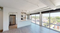 This 2-bedroom, 2-bathroom residence spans just under 1,000 square feet of contemporary living space across a single floor, featuring an open-concept layout flooded with natural light. Expansive floor-to-ceiling windows line the living areas and both bedrooms, offering panoramic elevated views of the surrounding cityscape and treeline, complemented by roll-down shades for privacy.

The kitchen is a standout feature, outfitted with white shaker cabinetry, sleek light quartz countertops, stainless steel appliances, and a large peninsula with an undermount sink — ideal for both cooking and entertaining. Pendant and track lighting add a modern industrial touch to the space.

Both bedrooms are generously proportioned, each featuring large windows with city views and ceiling fans. The unit includes two full bathrooms finished in light tile flooring and white vanities; one bathroom features a glass-enclosed walk-in shower. Each bedroom is served by a spacious walk-in closet with wire shelving for ample storage.

Additional highlights include in-unit Whirlpool washer and dryer, light wood-tone flooring throughout, and exposed ductwork that lends an industrial-modern aesthetic. The overall ambiance is bright, clean, and contemporary.