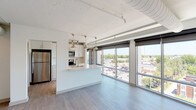 This 2-bedroom, 2-bathroom residence spans just under 1,000 square feet of contemporary living space across a single floor, featuring an open-concept layout flooded with natural light. Expansive floor-to-ceiling windows line the living areas and both bedrooms, offering panoramic elevated views of the surrounding cityscape and treeline, complemented by roll-down shades for privacy.

The kitchen is a standout feature, outfitted with white shaker cabinetry, sleek light quartz countertops, stainless steel appliances, and a large peninsula with an undermount sink — ideal for both cooking and entertaining. Pendant and track lighting add a modern industrial touch to the space.

Both bedrooms are generously proportioned, each featuring large windows with city views and ceiling fans. The unit includes two full bathrooms finished in light tile flooring and white vanities; one bathroom features a glass-enclosed walk-in shower. Each bedroom is served by a spacious walk-in closet with wire shelving for ample storage.

Additional highlights include in-unit Whirlpool washer and dryer, light wood-tone flooring throughout, and exposed ductwork that lends an industrial-modern aesthetic. The overall ambiance is bright, clean, and contemporary.