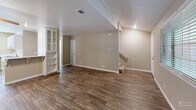 Located in Auburn, California, this two-story, two-bedroom, two-bathroom home offers a practical and comfortable layout spread across two floors. The main level features an open living and dining area with warm wood-look hardwood flooring, a ceiling fan, and a standout tile-hearth wood-burning stove that serves as a focal point of the room. A built-in white display cabinet transitions the space into the kitchen, which is equipped with white cabinetry, stainless steel appliances including a gas range and full-size refrigerator, and light stone countertops. A dedicated entrance and laundry area complete the main floor, along with staircase access to the upper level. Upstairs, two carpeted bedrooms each feature ceiling fans and direct closet access. The primary bedroom includes a spacious walk-in closet with dual hanging rods. Both bathrooms are clean and functional — one offering a glass-door walk-in shower with a frosted panel, and the other a full shower-tub combo with a window above. With five closets total throughout the home, storage is plentiful. Natural light filters through window blinds in the bedrooms, and the mature trees visible outside add a touch of greenery to the setting.