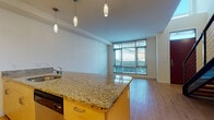 This well-appointed two-floor residence offers a thoughtfully designed layout that balances modern finishes with functional living. The main level greets you with light hardwood flooring throughout, crisp white walls, and a striking red entry door that adds a bold design accent. The open-concept kitchen and living area serves as the heart of the home, featuring a granite-topped island with pendant lighting, warm maple cabinetry, stainless steel appliances including a refrigerator, range, and over-the-range microwave, and generous counter space. Floor-to-ceiling windows flood the living area with natural light and provide views of the surrounding neighborhood, creating an airy and inviting atmosphere. The main level also includes a bathroom finished with granite countertops and maple cabinetry, consistent with the home's cohesive design language. A staircase leads to the upper level, where carpeted bedrooms offer a quiet retreat. The primary bedroom is bright and spacious, benefiting from wide windows with outdoor views. The upper-level bathroom continues the granite and maple theme, featuring a wide vanity with dual mirrors and access to a separate shower area. Additional storage is provided via a dedicated closet space. Throughout both floors, the clean, contemporary aesthetic is maintained with neutral tones and quality finishes.