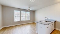 Located at 6200 Centurion Cir in Huber Heights, Ohio, this single-floor unit offers an efficiently designed layout that maximizes every square foot. The open-concept kitchen and living area serves as the heart of the space, featuring light wood-style flooring that extends throughout and neutral gray walls that create a clean, modern atmosphere. The kitchen is anchored by a peninsula with granite-style countertops and an integrated sink, complemented by white cabinetry and a full suite of stainless steel appliances, including a refrigerator, range, and microwave. A ceiling fan overhead provides both comfort and casual lighting to the combined living area, which also benefits from natural light streaming in through a window with exterior views. The open layout provides a versatile living space that flows seamlessly from cooking to relaxing. The bathroom is well-appointed with a full tub and shower surround in crisp white, chrome fixtures, and wood-style flooring that ties the unit together cohesively. A dedicated closet offers practical storage. The unit's consistent use of light tones, modern fixtures, and durable flooring throughout gives it a fresh, move-in-ready character suited for efficient, contemporary living.